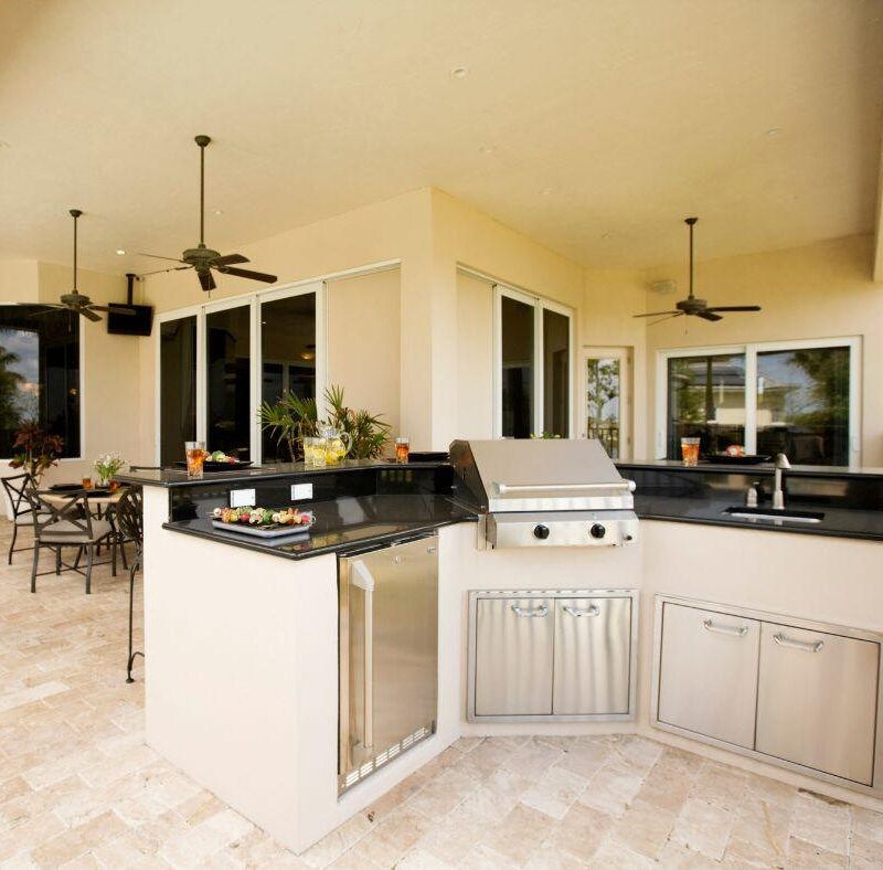 covered outdoor kitchen bar area with countertops, cabinet storage, and a stainless steel grill