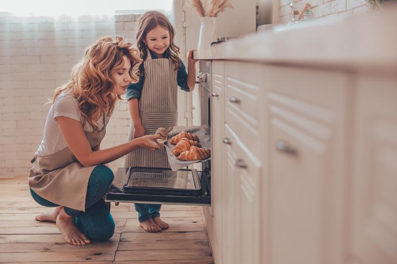 mom and daughter checking on baked goods in their oven