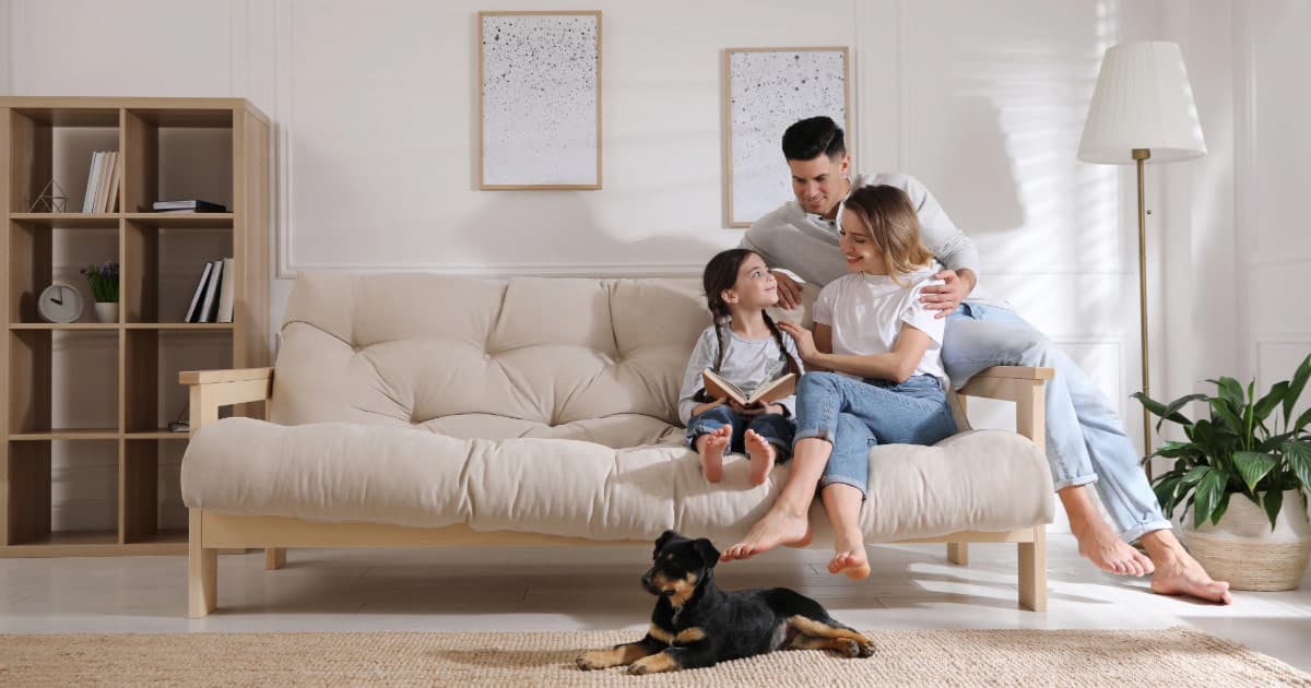 Mom, dad, daughter, and puppy sitting comfortably in their living room