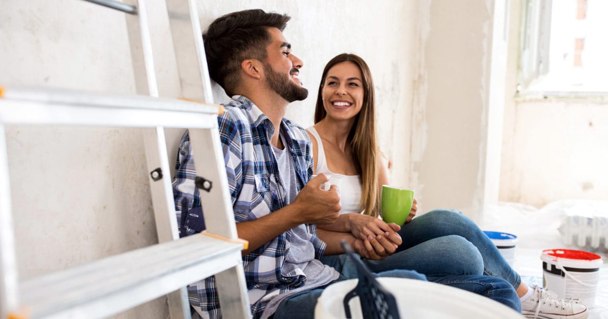 Young husband and wife sitting in a room taking a break from painting