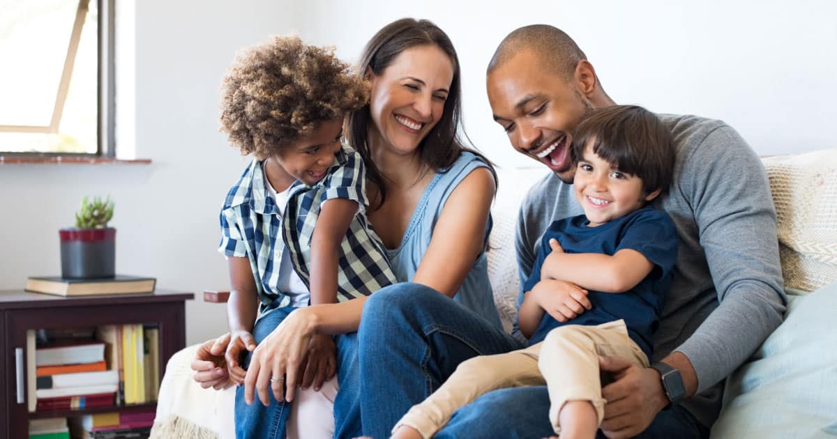 Young couple sitting on their sofa laughing with kids