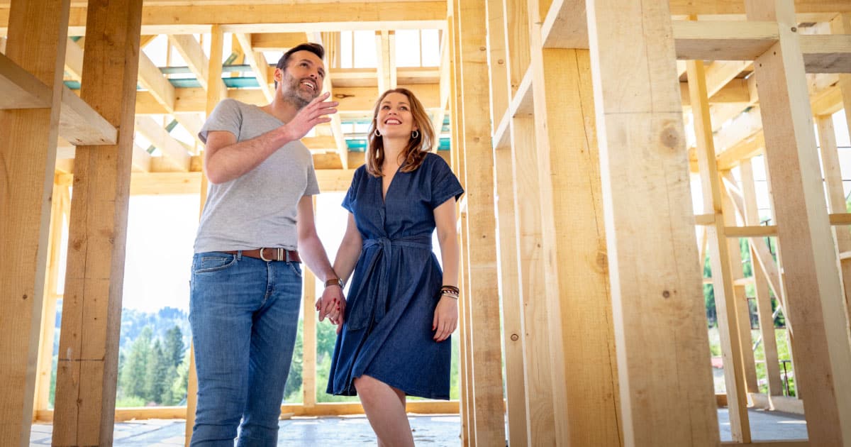 Couple walking through their home's new construction during framing phase