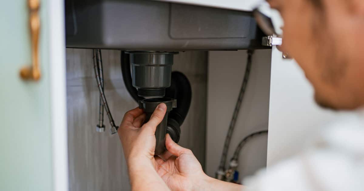 Plumber checking for leaks under the kitchen sink