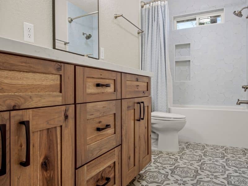 bathroom with white and grey printed tile and brown wood cabinets with a tub and shower.
